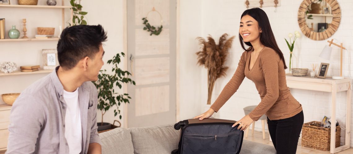 Vacation Concept. Joyful Travelers Couple Packing Suitcase For Vacation At Home. Selective Focus